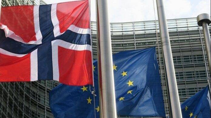 Bilde av norsk flagg og EU-flagget utenfor bygget til Europakommisjonen