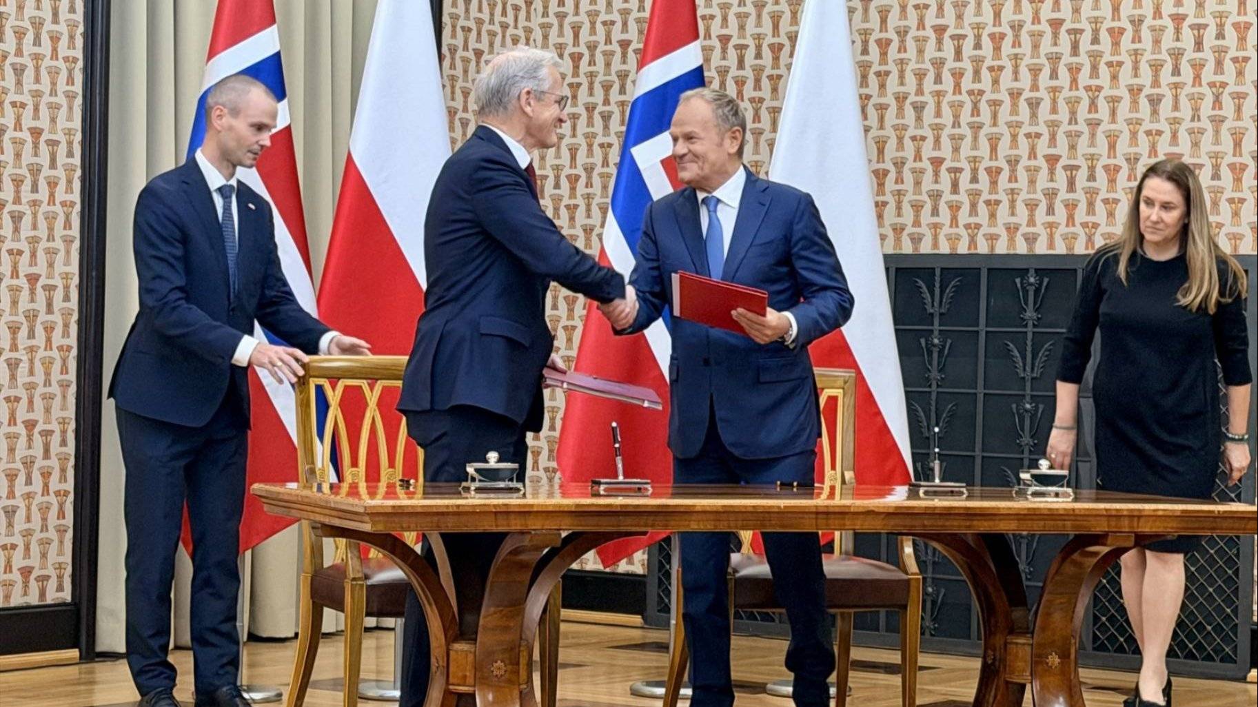 Bilde av den norske og polske statsministeren som håndhilser foran norske og polske flagg. 