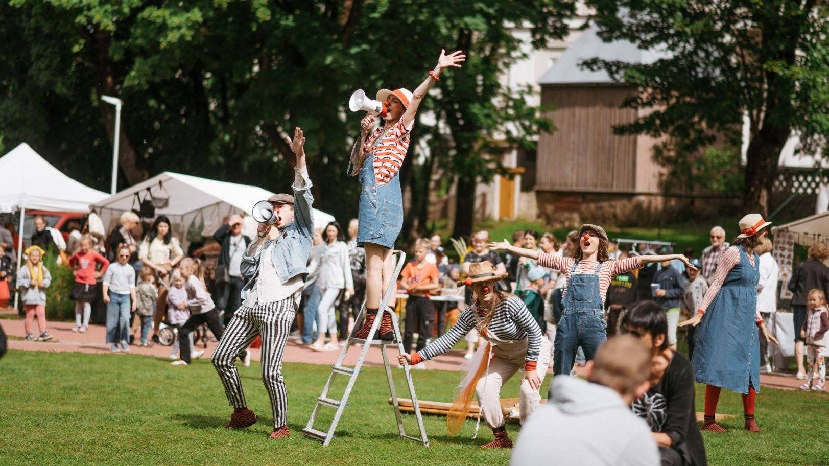 Norsk flagg som vaier mellom tradisjonelle tørkestativer for fisk, med fjell og blå himmel i bakgrunnen.