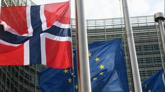Bilde av norsk flagg og EU-flagg som vaier i vinden utenfor Europakommisjonen
