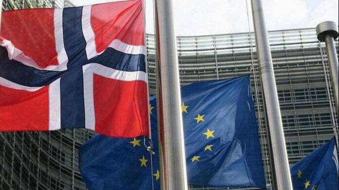 Bilde av norsk flagg og Eu flagg som blafrer i vinden utenfor Kommisjonen