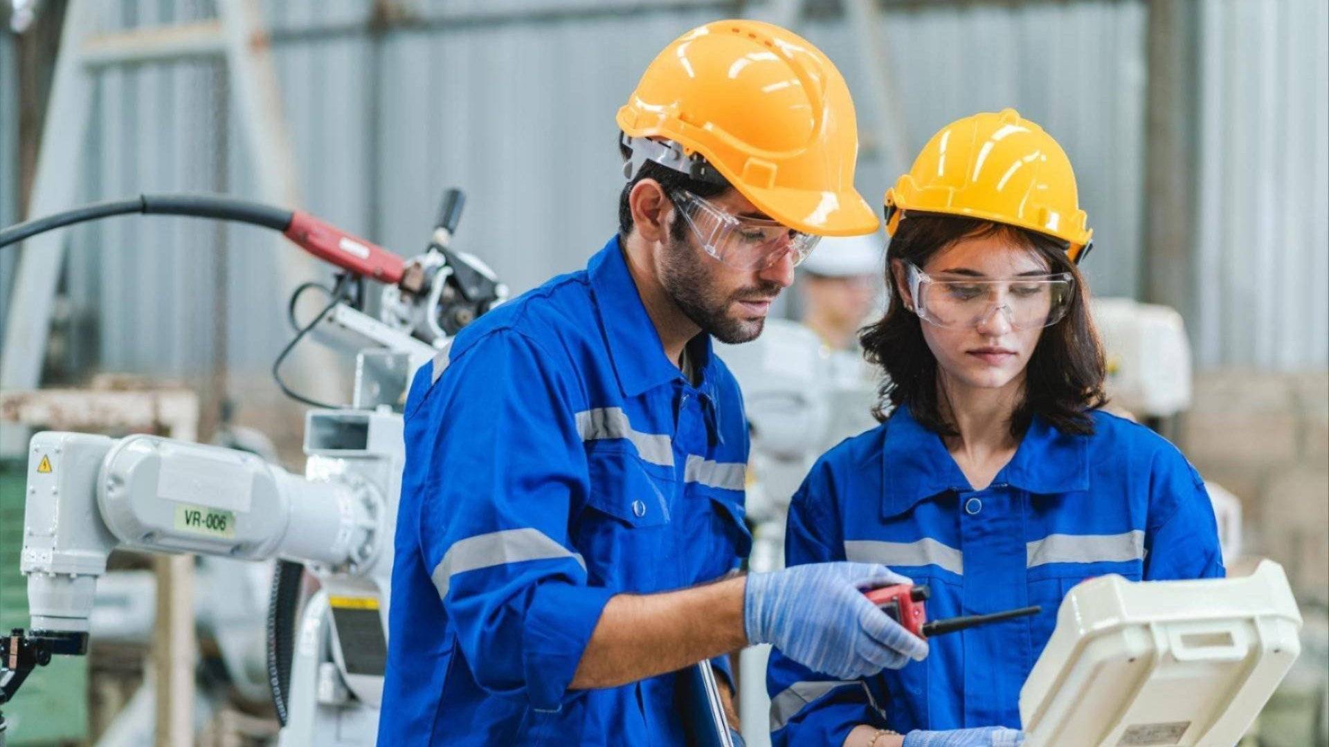 To fabrikkarbeidere med gule hjelmer